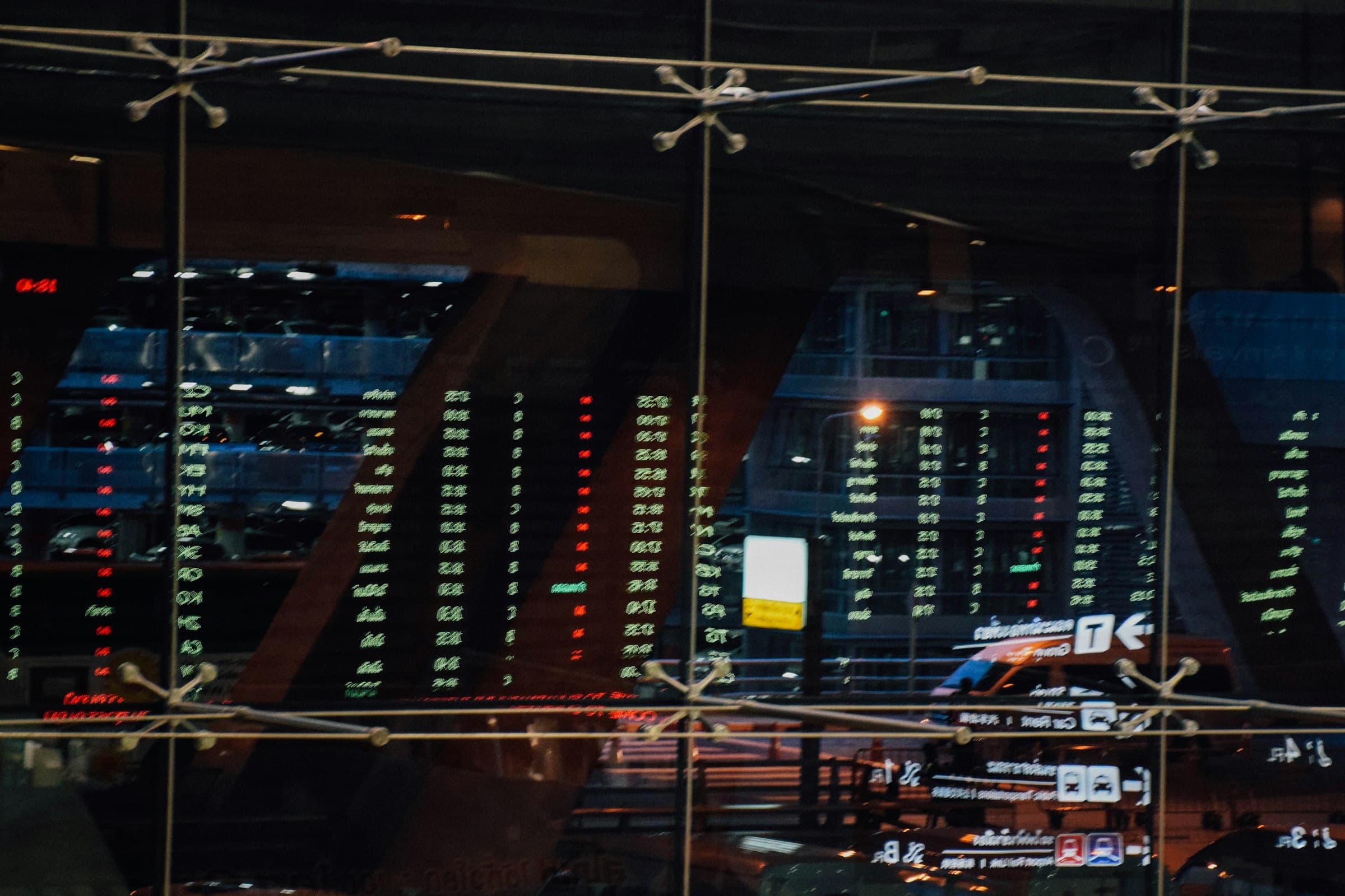 Stock prices on an exchange board, reflected in glass at night